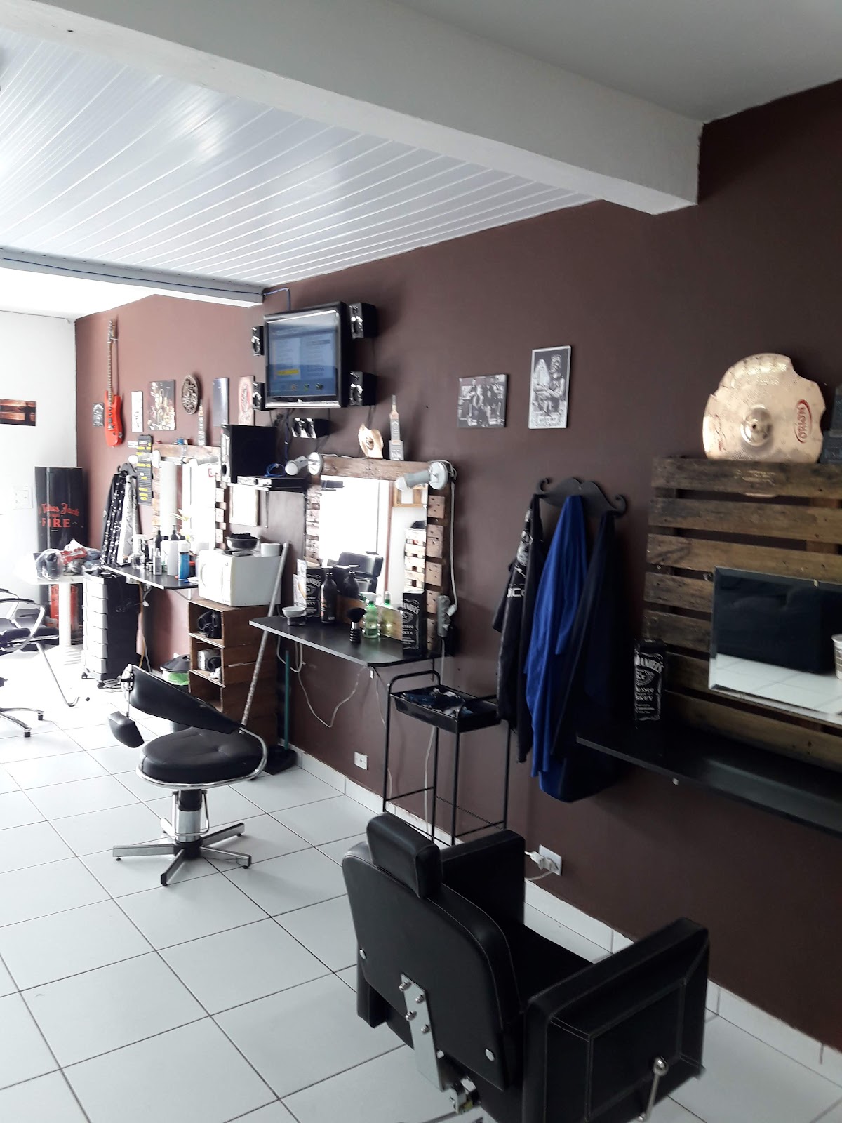 Salão da Barbearia Rock Star com guitarra, prato de bateria e parede marrom vinho